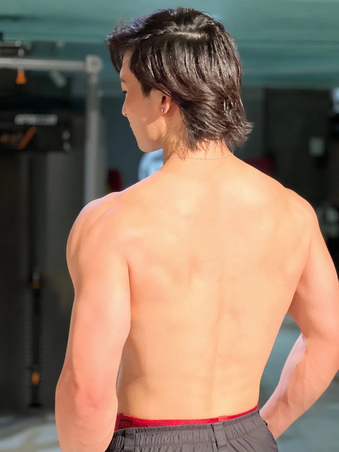 ジムで背中を向けて佇む松田健志の後ろ姿
